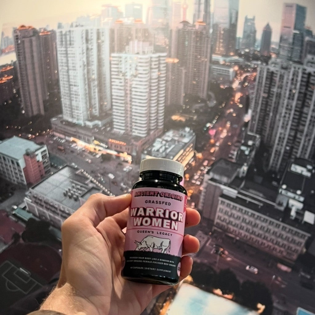 Hand holding Ancient Origins Warrior Women grass-fed beef organ supplement bottle — real nutrition for women's hormonal health, energy and vitality